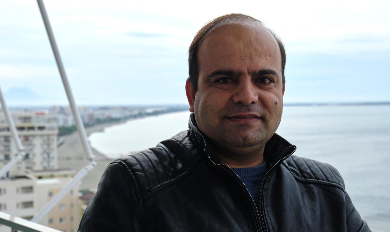 Faisal Karimi trägt eine schwarze Lederjacke. Hinter ihm ist das Meer und der Strand zu sehen. Faisal Karimi trägt eine schwarze Lederjacke. Hinter ihm ist das Meer und der Strand zu sehen.