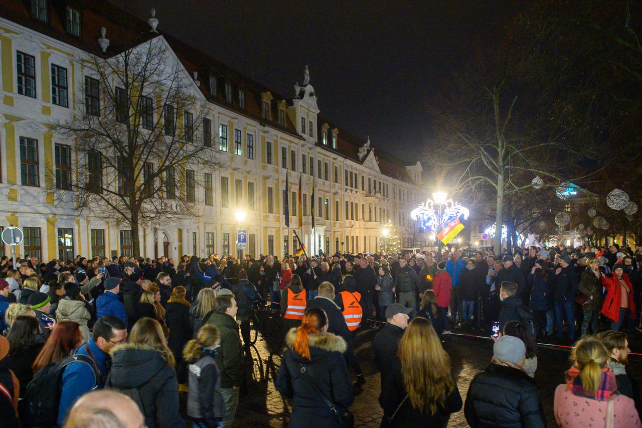 Gegendemonstranten bilden mit einem Absperrband eine Menschenkette und gehen vor dem Landtag in Magdeburg an einer Ansammlung von Menschen vorbei, die sich auf dem Domplatz versammelt haben, um gegen die Corona-Maßnahmen in Sachsen-Anhalt zu protestieren. Gegendemonstranten bilden mit einem Absperrband eine Menschenkette und gehen vor dem Landtag in Magdeburg an einer Ansammlung von Menschen vorbei, die sich auf dem Domplatz versammelt haben, um gegen die Corona-Maßnahmen in Sachsen-Anhalt zu protestieren.
