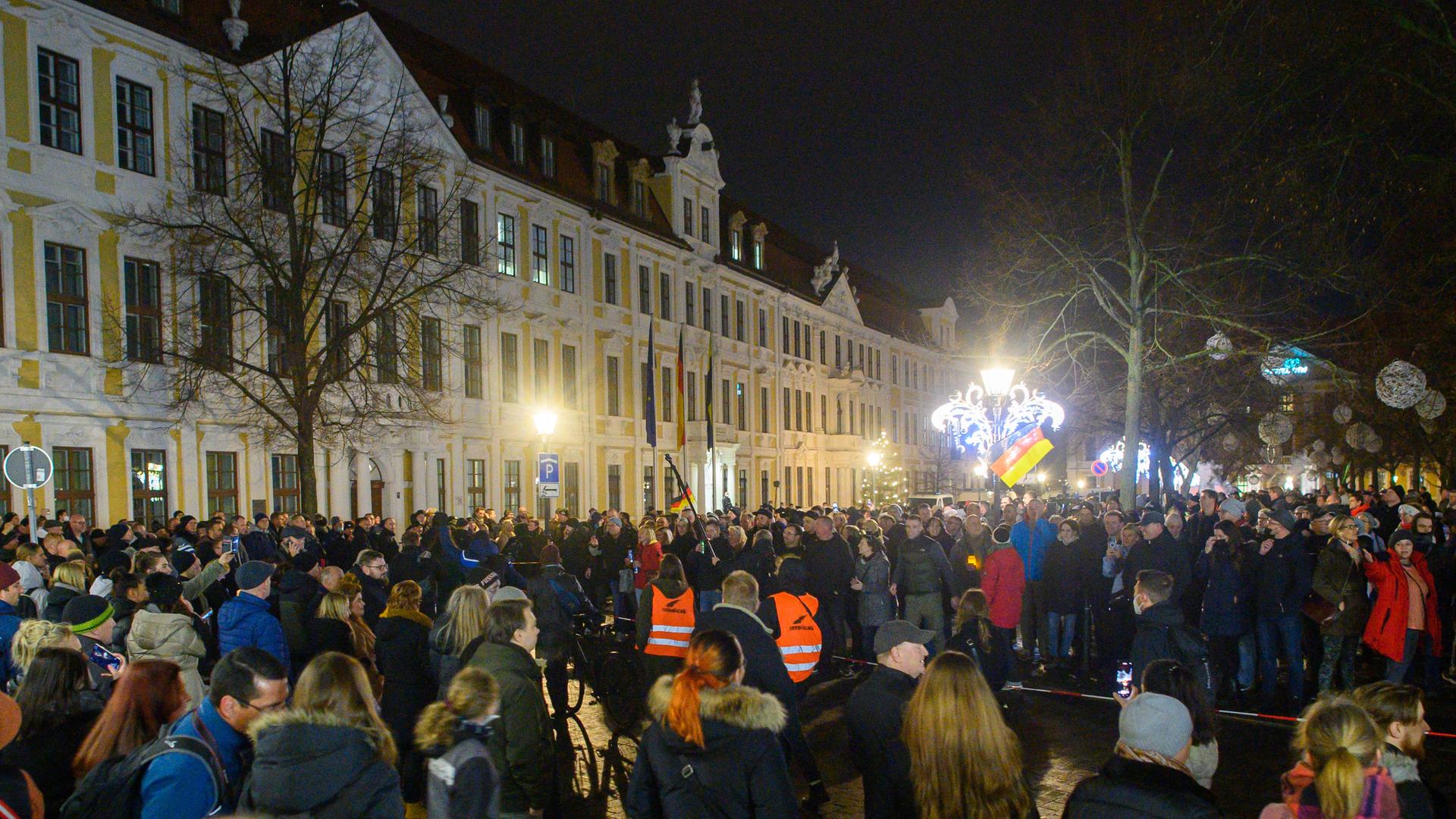 Gegendemonstranten bilden mit einem Absperrband eine Menschenkette und gehen vor dem Landtag in Magdeburg an einer Ansammlung von Menschen vorbei, die sich auf dem Domplatz versammelt haben, um gegen die Corona-Maßnahmen in Sachsen-Anhalt zu protestieren.