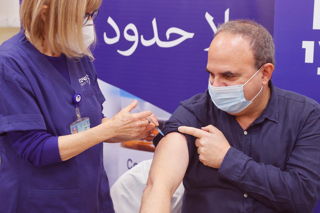 Ein Mann erhält in Israel seine vierte Impfung gegen das Coronavirus. Im Hintergrund steht auf hebräisch "Grenzenlose Hoffnung". Ein Mann erhält in Israel seine vierte Impfung gegen das Coronavirus. Im Hintergrund steht auf hebräisch "Grenzenlose Hoffnung".