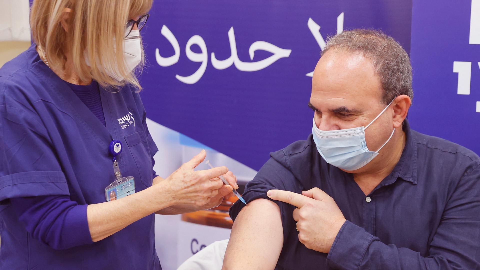 Ein Mann erhält in Israel seine vierte Impfung gegen das Coronavirus. Im Hintergrund steht auf hebräisch "Grenzenlose Hoffnung". Ein Mann erhält in Israel seine vierte Impfung gegen das Coronavirus. Im Hintergrund steht auf hebräisch "Grenzenlose Hoffnung".