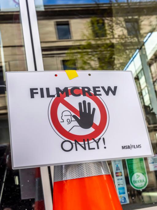 An einer Glastür ist ein Stoppschild mit der Aufschrift "Filmcrew Only!" angebracht.