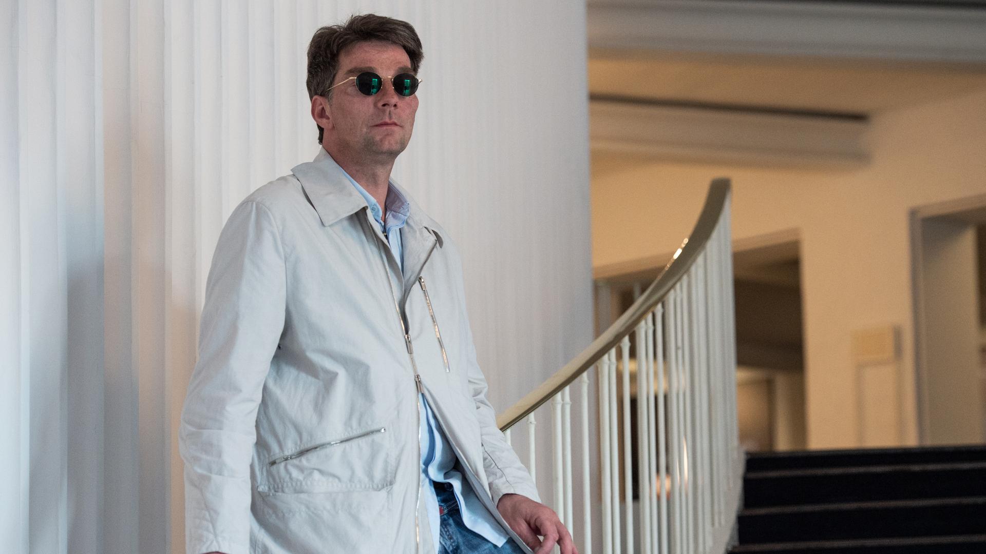 Marco Goecke im April 2019, als er designierter Balletdirektor der Staatsoper Hannover war. Er steht in einem hellen Mantel und mit runder Sonnenbrille auf einer Treppe im Foyer der Staatsoper. Marco Goecke im April 2019, als er designierter Balletdirektor der Staatsoper Hannover war. Er steht in einem hellen Mantel und mit runder Sonnenbrille auf einer Treppe im Foyer der Staatsoper.
