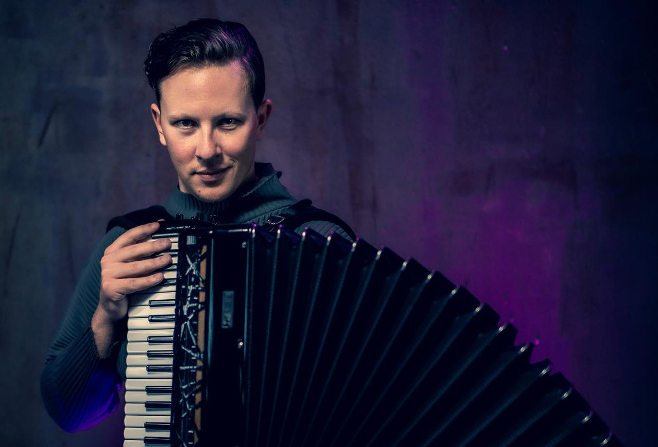 Martynas Levicki mit kurzen dunklen Haaren schaut direkt in die Kamera, während er sein Instrument weit auffächert. Martynas Levicki mit kurzen dunklen Haaren schaut direkt in die Kamera, während er sein Instrument weit auffächert.