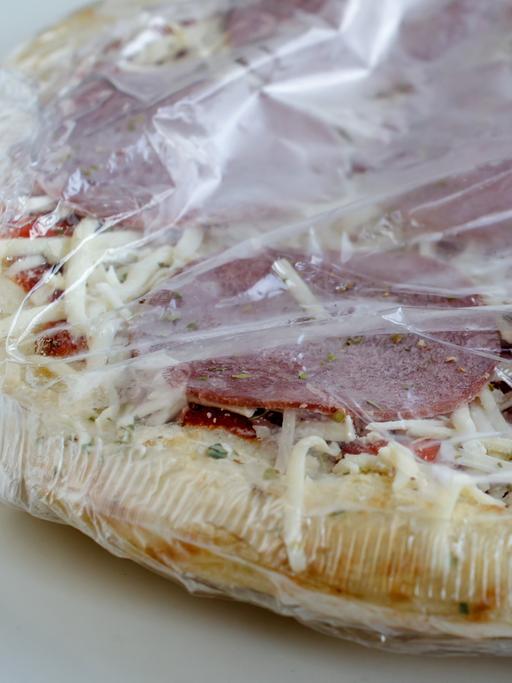 Tiefgekühlte Pizza aus der Packung als Convenience Food, noch in Folie verpackt