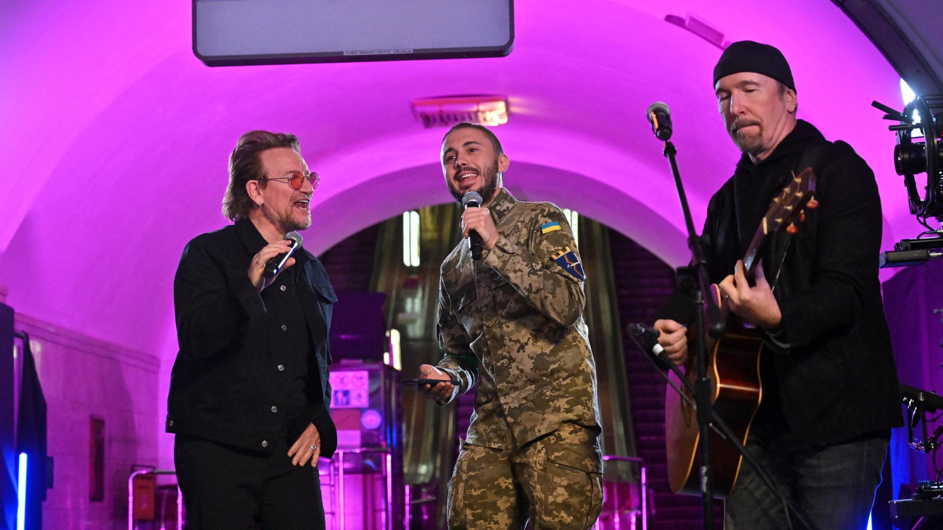 Drei Männer stehen auf einer Bühne und singen. Drei Männer stehen auf einer Bühne und singen.