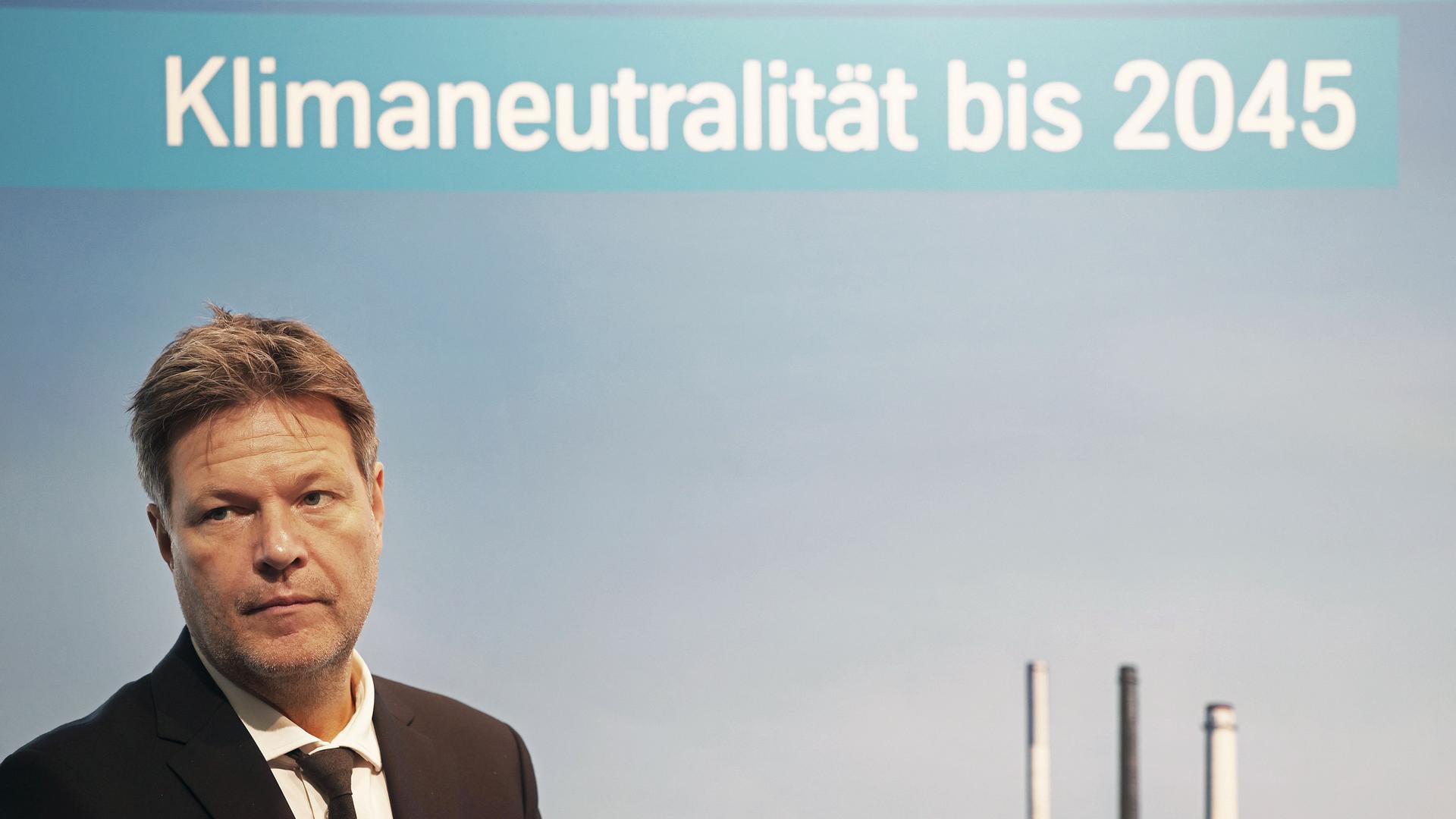 Robert Habeck (Bündnis 90/Die Grünen), Bundesminister für Wirtschaft und Klimaschutz, steht vor einem Plakat mit Aufschrift "Klimaneutralität bis 2045". 