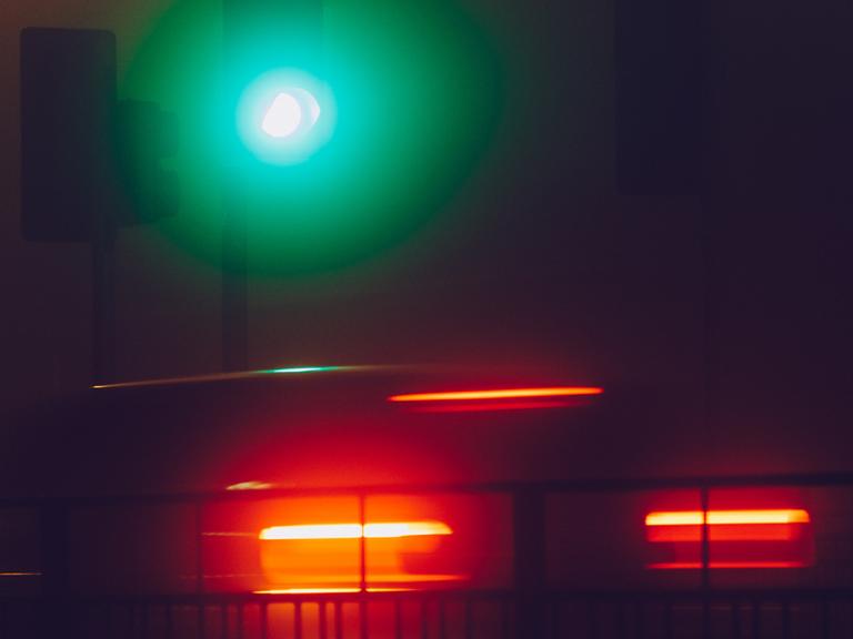 Eine grün leuchtende Ampel im nächtlichen Nebel.