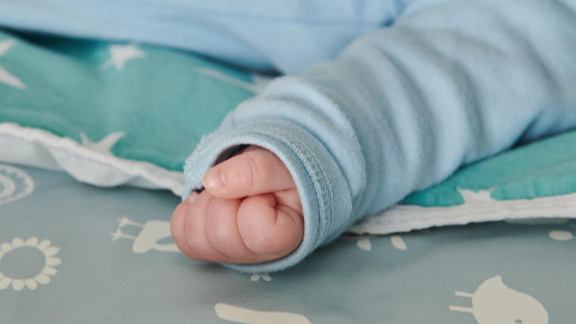 Die Hand eines nur wenige Wochen alten Babys ist zu einer kleinen Faust geballt. Die Hand eines nur wenige Wochen alten Babys ist zu einer kleinen Faust geballt.