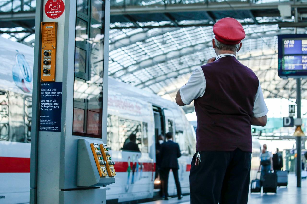 Ein Schaffner gibt das Abfahrtszeichen für einen ICE auf dem Bahnsteig im Berliner Hauptbahnhof. 