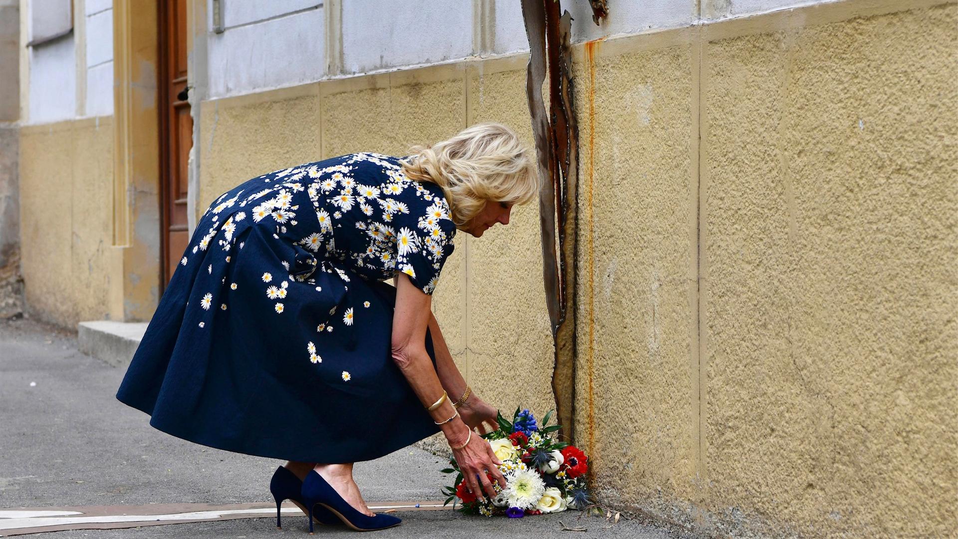 Jill Biden legt vor einem Gebäude einen Kranz ab und kniet nieder dabei Jill Biden legt vor einem Gebäude einen Kranz ab und kniet nieder dabei