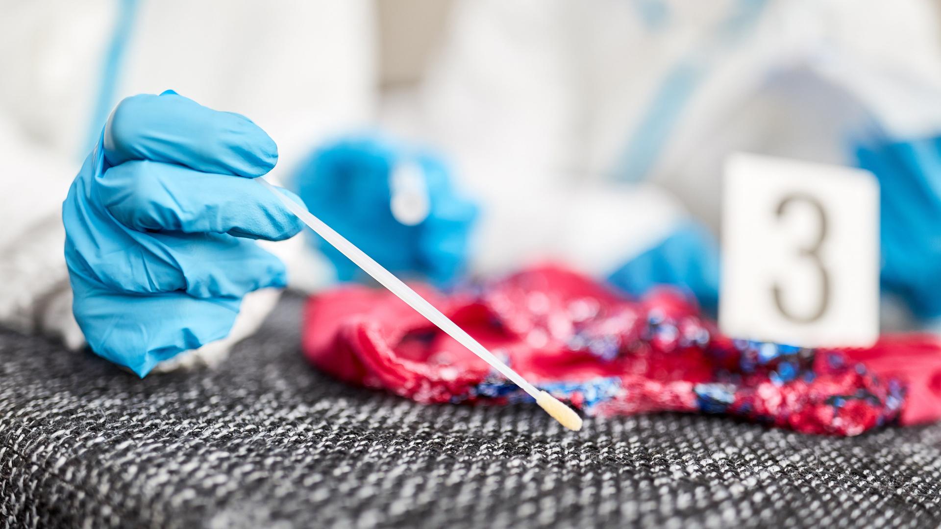 Kriminaltechniker nehmen mit einem Wattestäbchen eine DNA-Probe. Kriminaltechniker nehmen mit einem Wattestäbchen eine DNA-Probe.