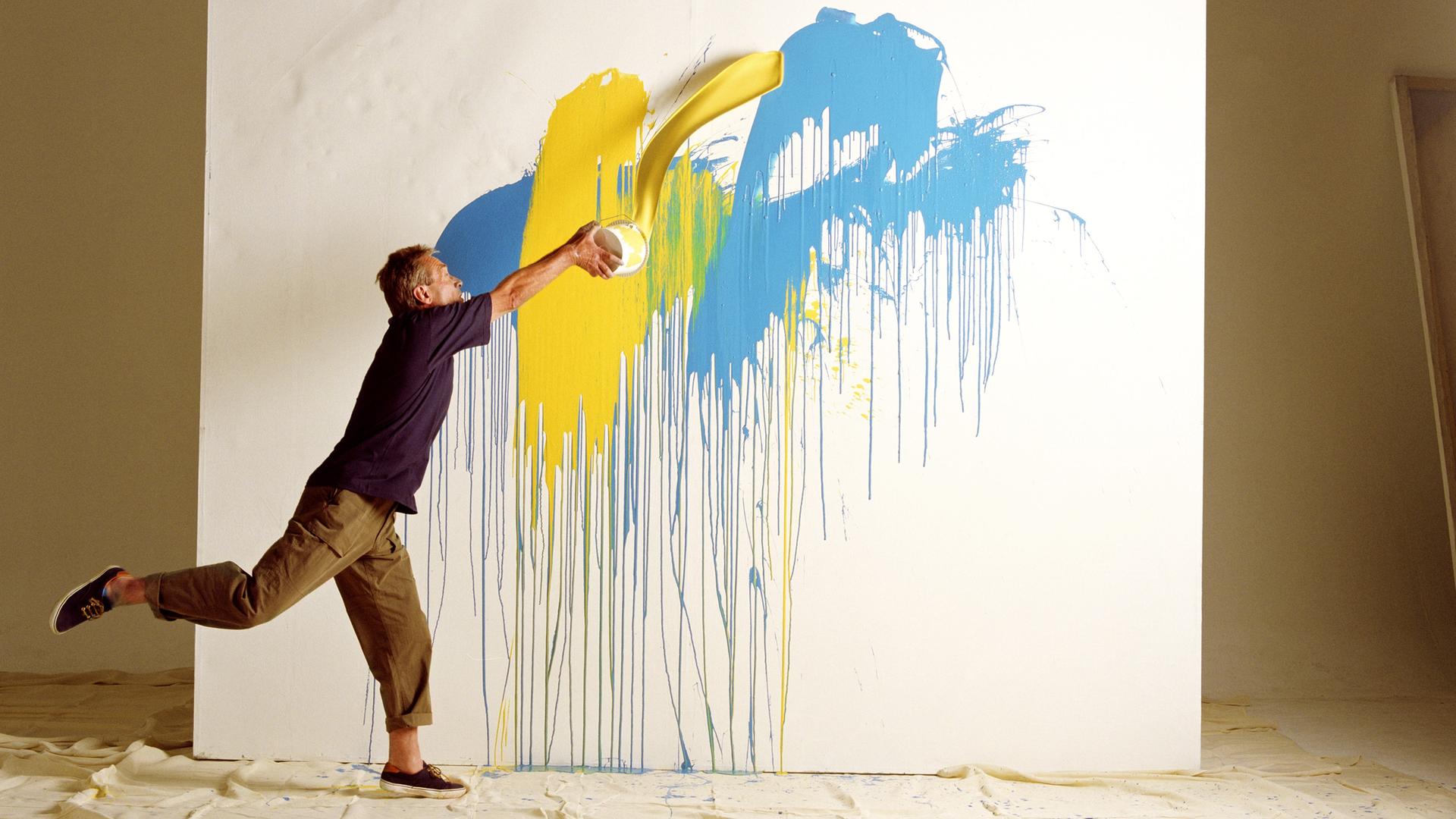 Ein Mann wirft Farben auf eine Leinwand. Ein Mann wirft Farben auf eine Leinwand.