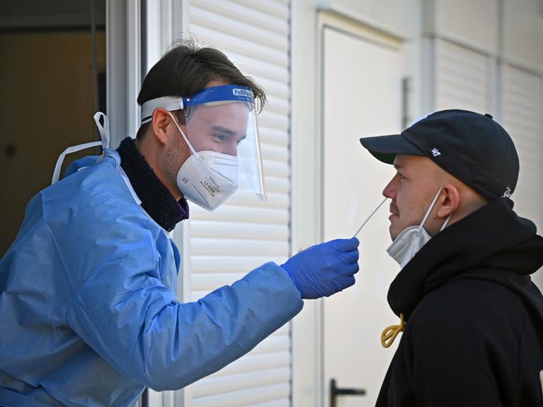 An einem Corona-Testzentrum wird einem Mann ein Nasenabstrich abgenommen. 