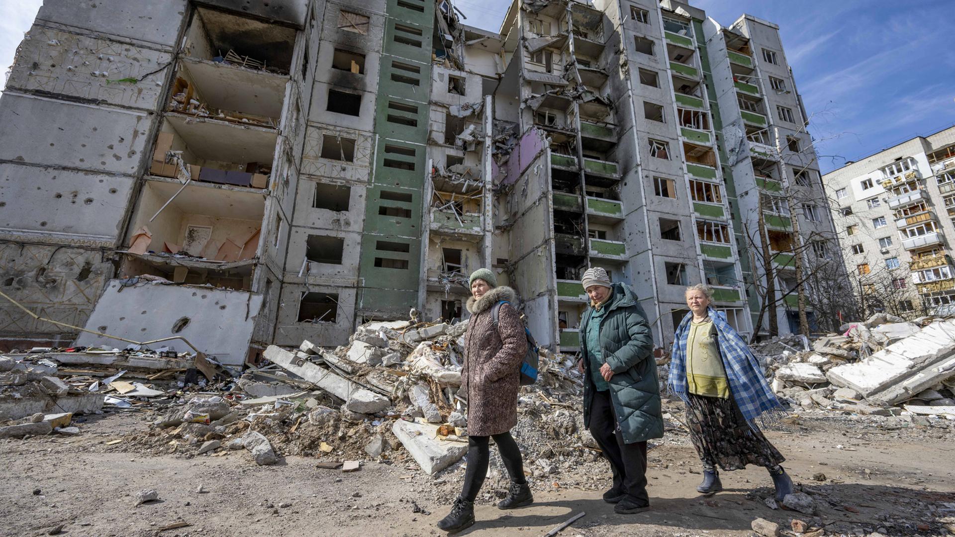 Drei Frauen stehen vor einem zerbombten Wohn-Hochhaus in Chernihiv, Ukraine Drei Frauen stehen vor einem zerbombten Wohn-Hochhaus in Chernihiv, Ukraine