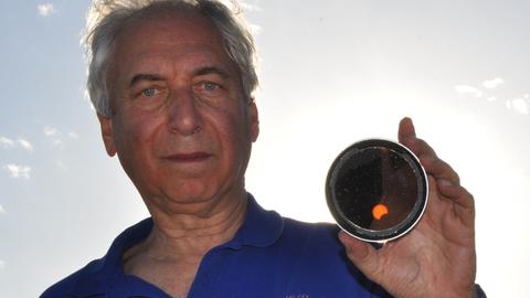 Jay Pasachoff hält einen kleinen Spiegel in der Hand, in der man eine partielle Sonnenfinsternis sehen kann.