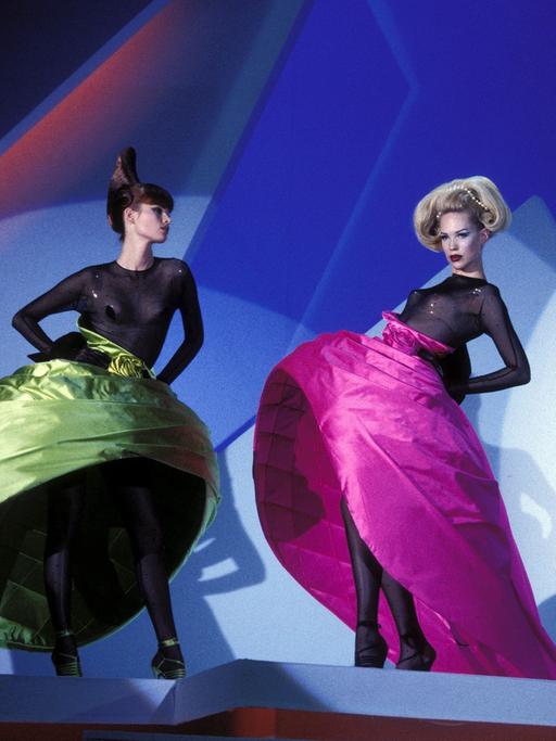 Prêt-à-porter-Modenschau der Herbst-Winter Kollektion 95-96 in Paris von Thierry Mugler. Zu sehen sind drei Modelle mit aufwendig gestalteten, opulenten und farbenfrohen Kleidern.