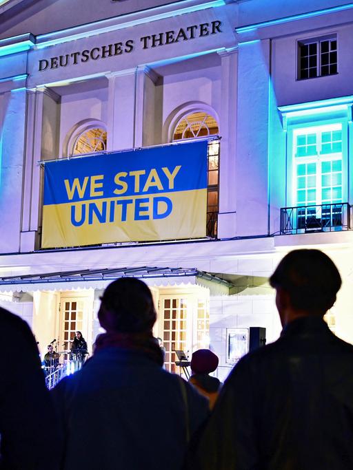Fassade des Deutsches Theater in Berlin, über dem Eingang hängt ein blau-gelbes Banner mit der Aufschrift "we stay united".