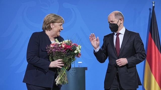 Bundeskanzler Scholz übergibt der bisherigen Kanzlerin Merkel einen Blumen-Strauß