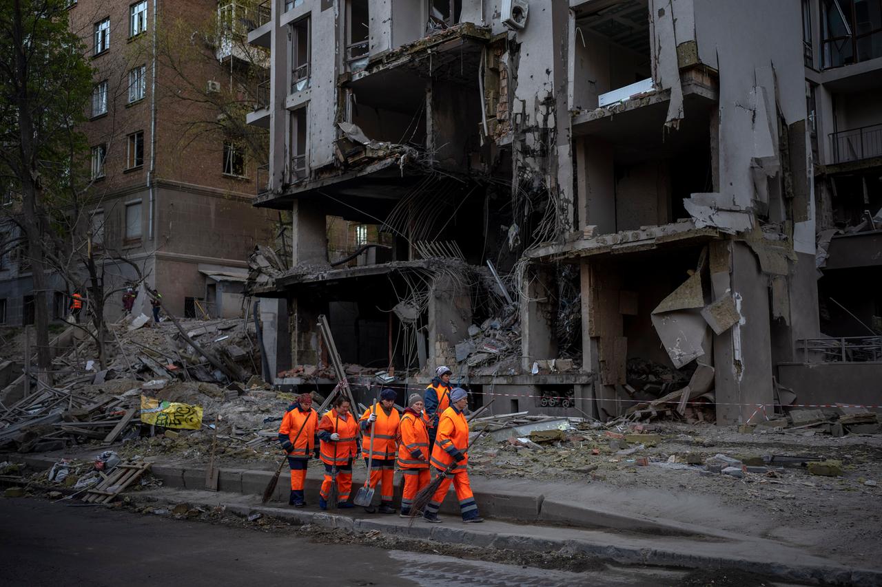 Arbeiter eines Aufräumtrupps in Kiew vor einem Gebäude nach einer Explosion.