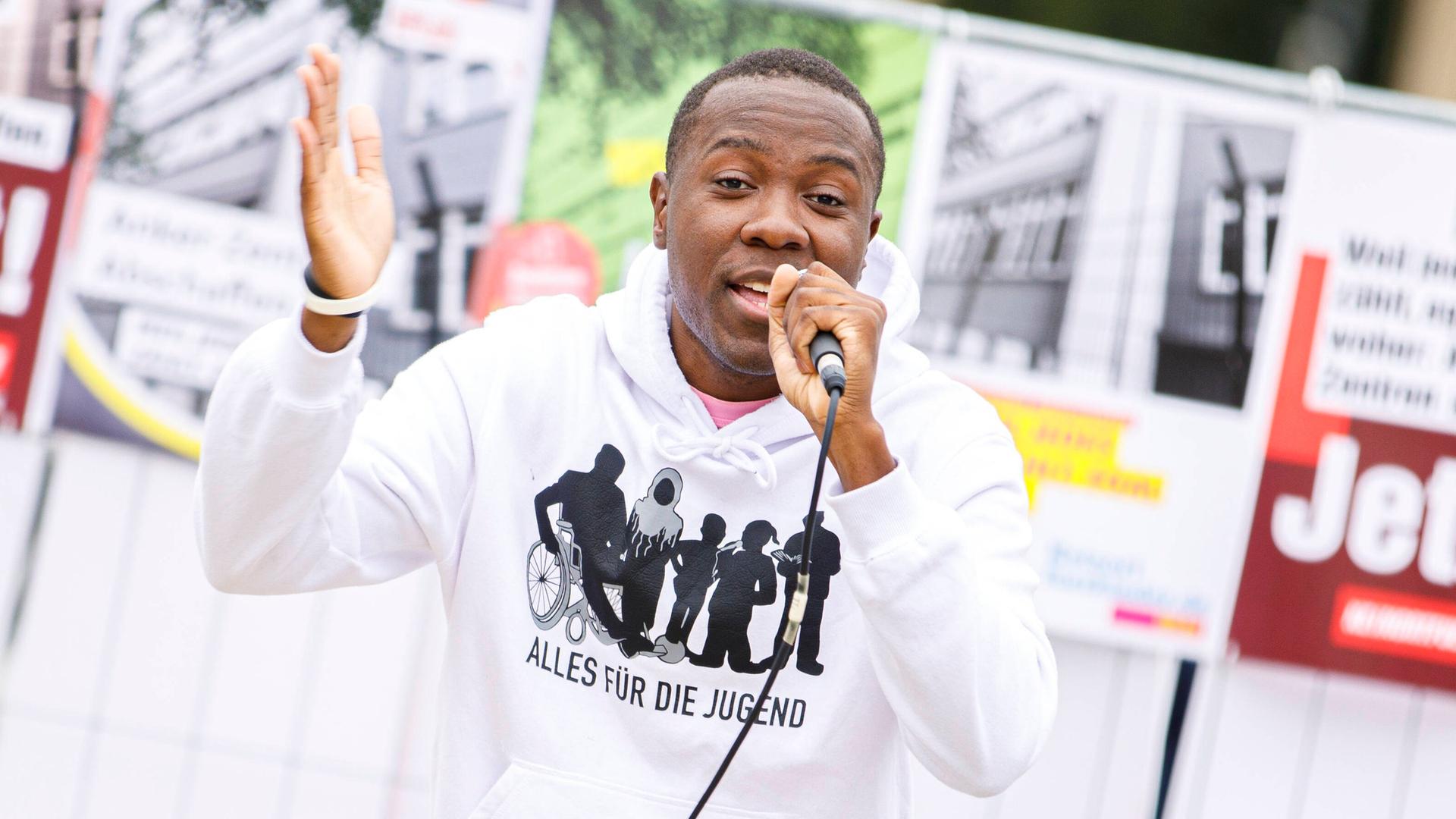 Matondo Castlo singt vor dem Brandenburger Tor in Berlin. Im Hintergrund zu sehen sind Transparente, die für mehr Kinderrechte werben. Matondo Castlo singt vor dem Brandenburger Tor in Berlin. Im Hintergrund zu sehen sind Transparente, die für mehr Kinderrechte werben.