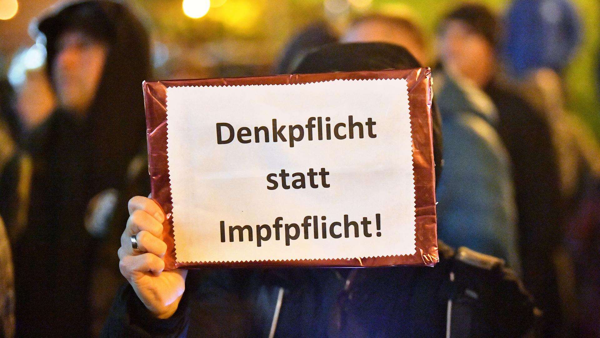 "Denkpflicht statt Impfpflichtt" steht auf dem Plakat, das eine Frau bei einer Demonstration vor dem Thüringer Landtag in den Händen hält "Denkpflicht statt Impfpflichtt" steht auf dem Plakat, das eine Frau bei einer Demonstration vor dem Thüringer Landtag in den Händen hält