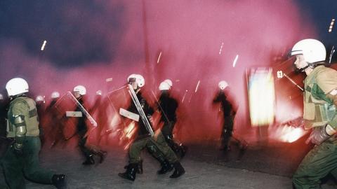 Polizisten rennen während eines rassisitischen Anschlages mit Molotow-Cocktails in Rostock-Lichtenhagen vor 30 Jahren.