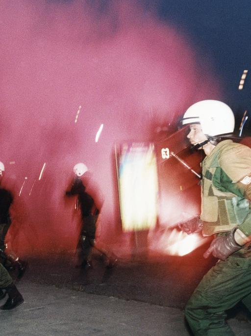 Polizisten rennen während eines rassisitischen Anschlages mit Molotow-Cocktails in Rostock-Lichtenhagen vor 30 Jahren.