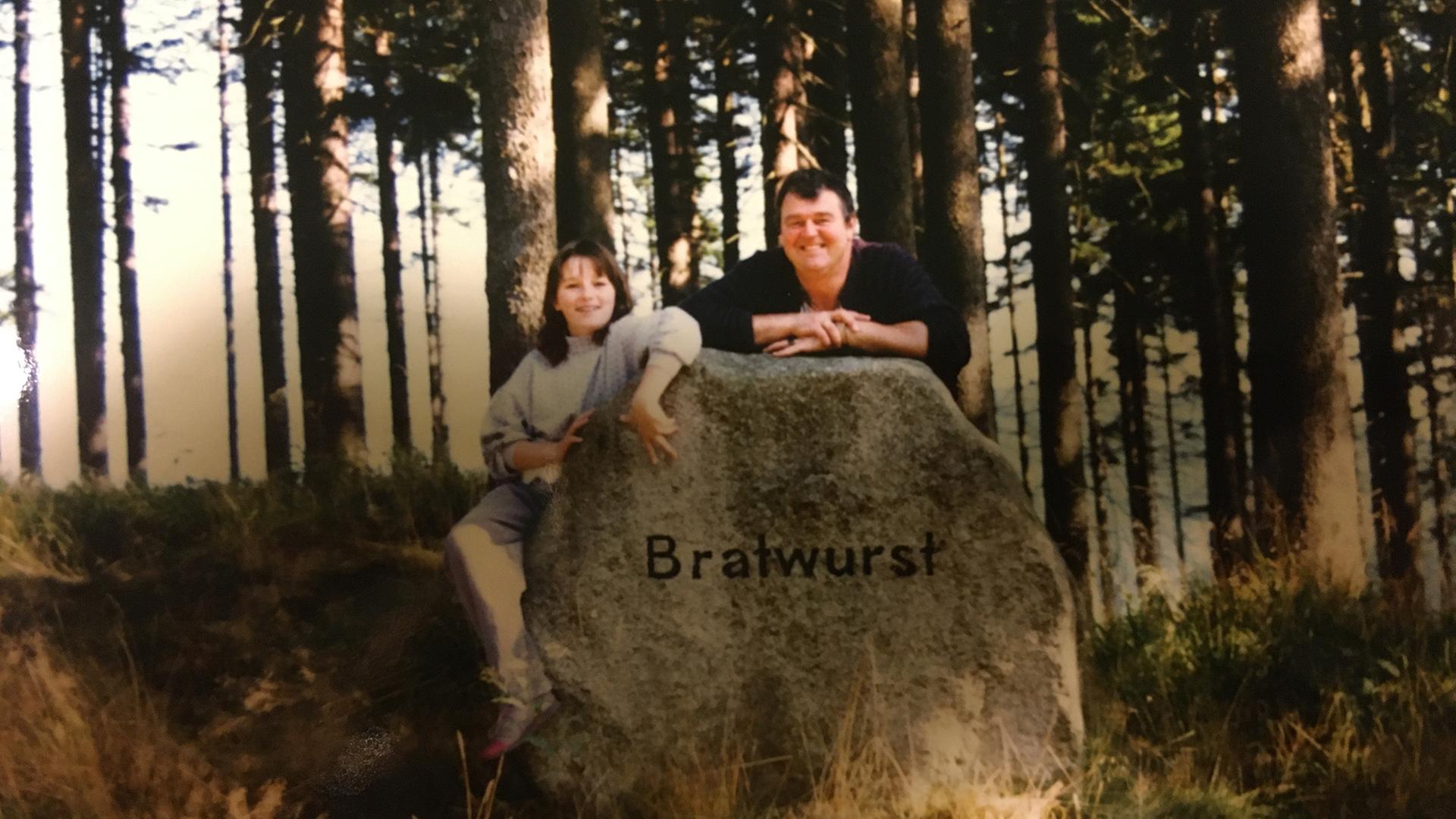Eine Frau und ein Mann stehen hinter einem Felsen, auf dem "Bratwurst" steht. Eine Frau und ein Mann stehen hinter einem Felsen, auf dem "Bratwurst" steht.
