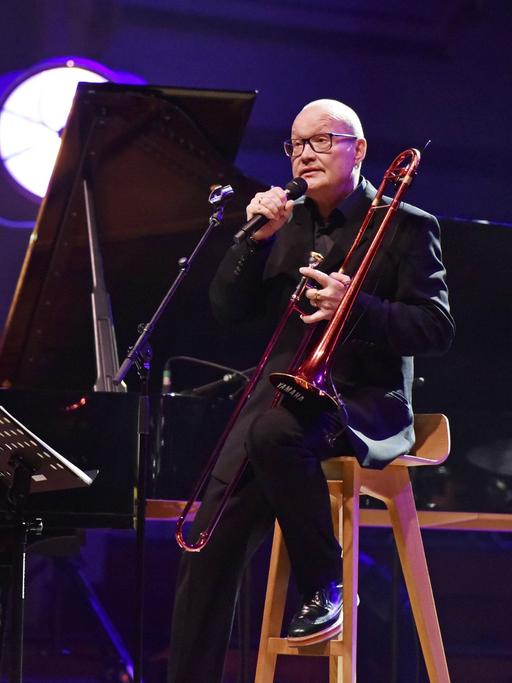 Michael Wollny begleitet Nils Landgren (Posaune) am Klavier auf einer rot-blau ausgeleuchteten Bühne in Hamburg im Jahr 2019. 