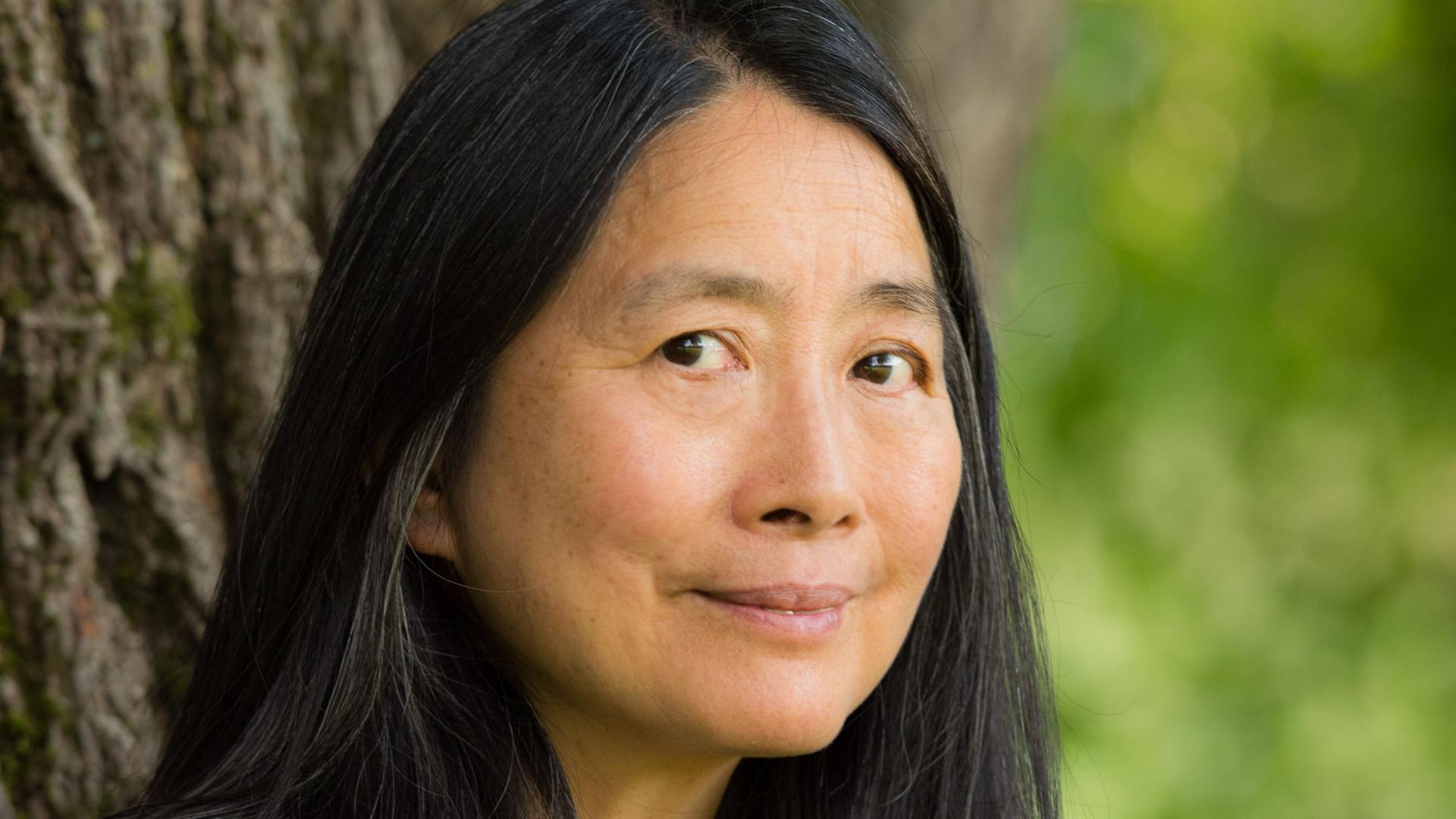 Portrait von Pi-hsien Chen vor einem Baumstamm Portrait von Pi-hsien Chen vor einem Baumstamm