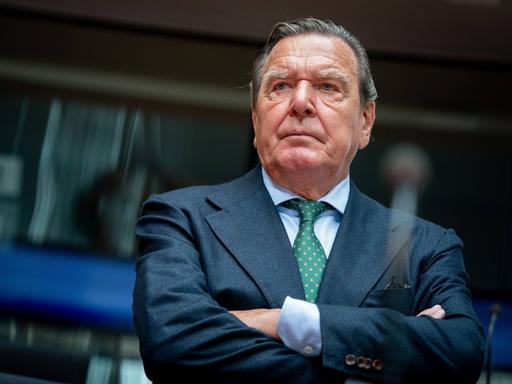 Gerhard Schröder (SPD), ehemaliger Bundeskanzler im Anzug mit verschränkten Armen in einem Sitzungsaal des Bundestages.