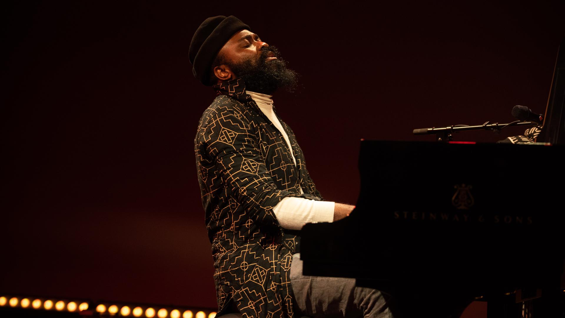 Ein bärtiger Mann mit schwarzer Wollmütze spielt zurückgelehnt mit geschlossenen Augen auf einer Bühne Klavier.