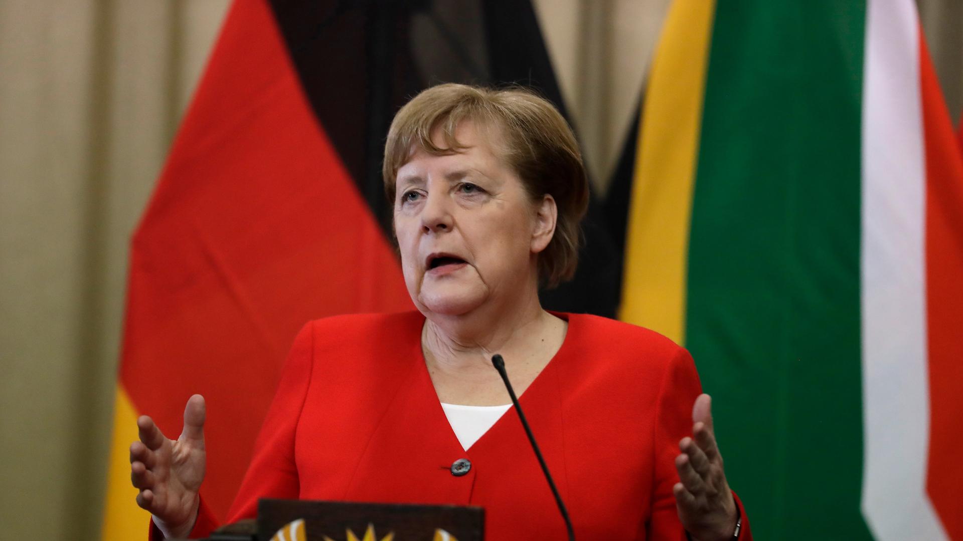 Die frühere Bundes-Kanzlerin Angela Merkel steht bei einer Presse-Konferenz hinter dem Redner-Pult. Das war auf einer Reise in das Land Süd-Afrika. Die frühere Bundes-Kanzlerin Angela Merkel steht bei einer Presse-Konferenz hinter dem Redner-Pult. Das war auf einer Reise in das Land Süd-Afrika.