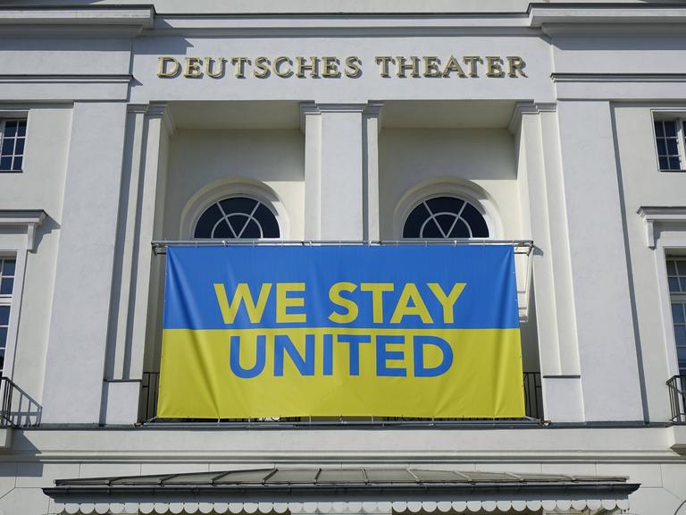 Die blau-gelbe Flagge der Ukraine mit der Aufschrift "We stay united" hängt am Deutschen Theater Berlin.