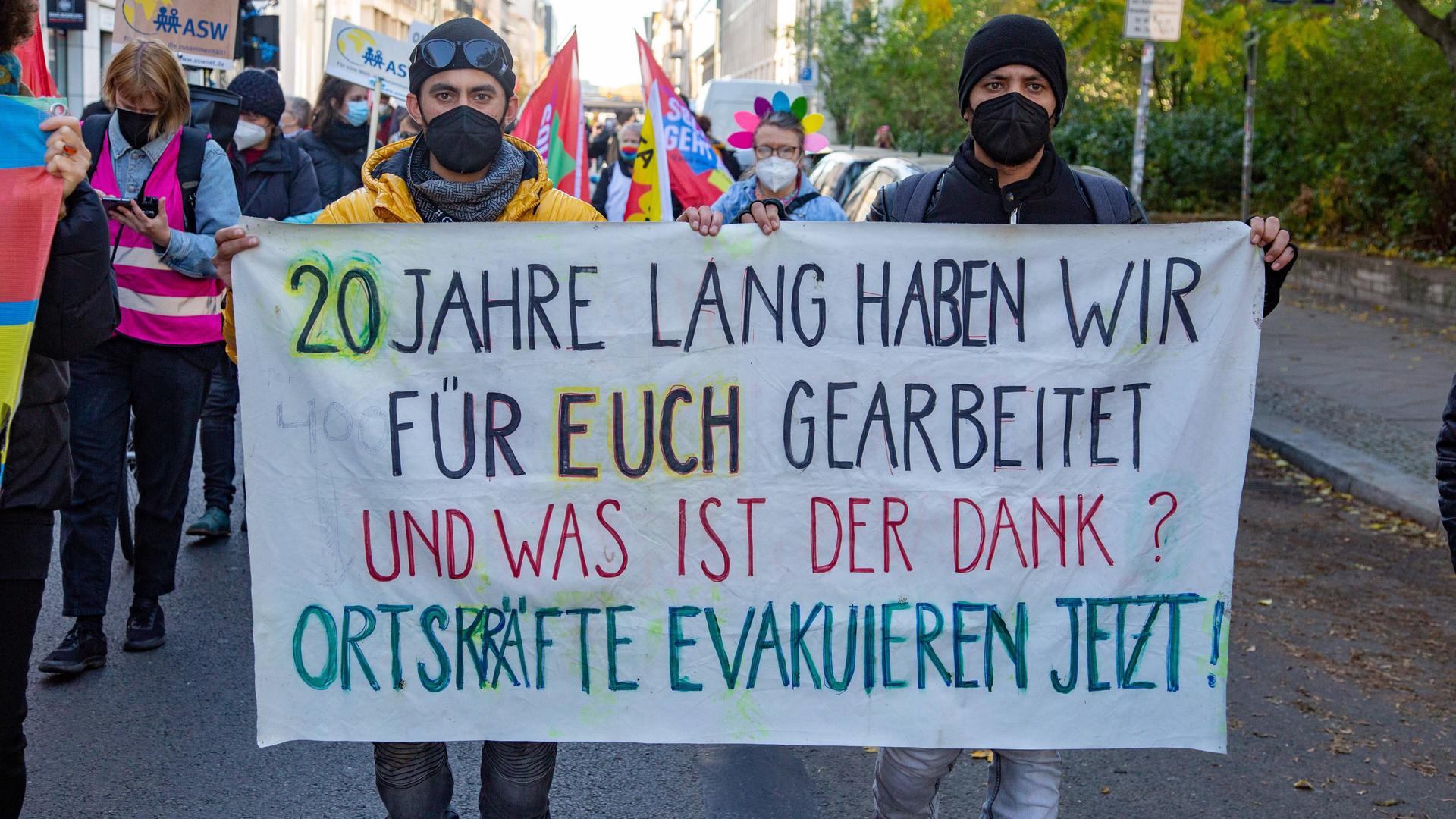 Afghanen halten auf einer Demo ein Transparen hoch mit der Aufschrift: "20 Jahre lang haben wir für euch gearbeitet und was ist der Dank? Ortskräfte evakuieren jetzt!" Afghanen halten auf einer Demo ein Transparen hoch mit der Aufschrift: "20 Jahre lang haben wir für euch gearbeitet und was ist der Dank? Ortskräfte evakuieren jetzt!"