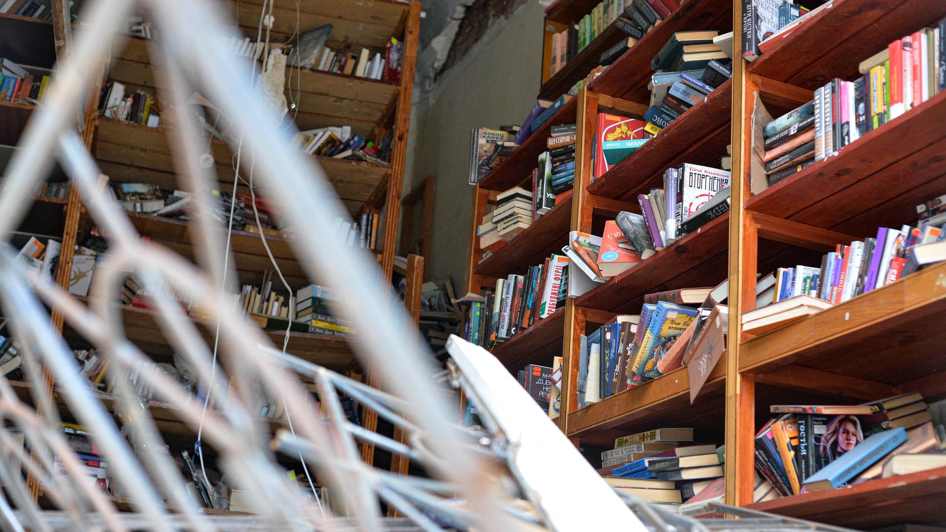 Zerstörte Bibliothek: Metall ragt in den Raum, in kaputten Regalen stehen noch Bücher.