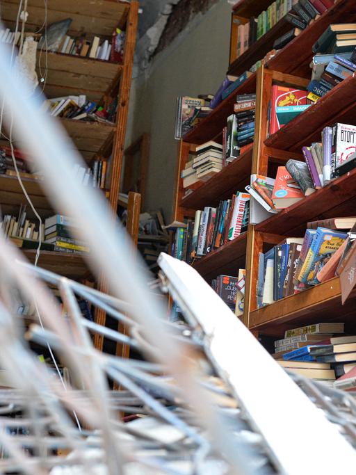 Zerstörte Bibliothek: Metall ragt in den Raum, in kaputten Regalen stehen noch Bücher.