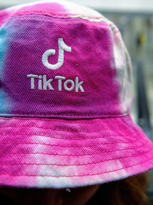 Eine Frau traegt am einen Hut mit dem Logo der Social Media Plattform Tik Tok.
