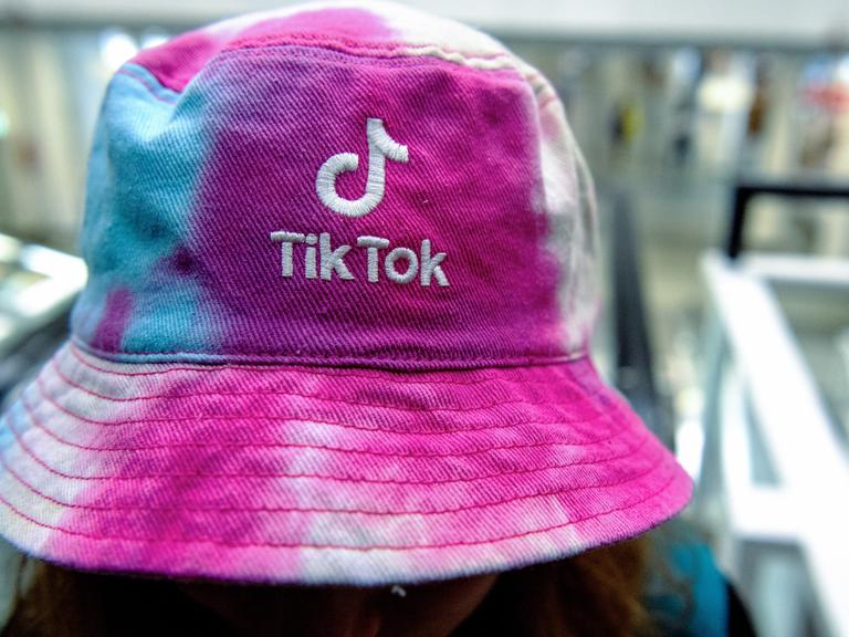Eine Frau traegt am einen Hut mit dem Logo der Social Media Plattform Tik Tok.