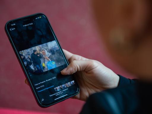 Eine Person betrachtet Fotos aus der Ukraine auf ihrem Handy an.