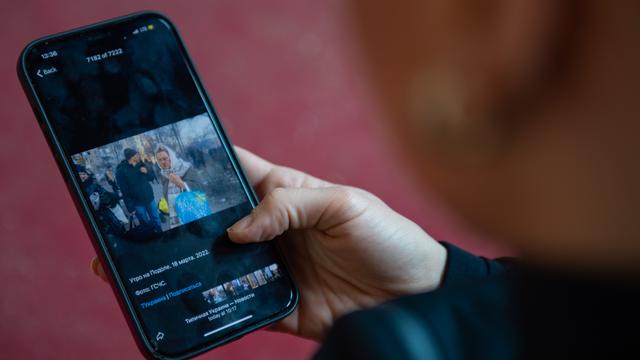 Eine Person betrachtet Fotos aus der Ukraine auf ihrem Handy an. Eine Person betrachtet Fotos aus der Ukraine auf ihrem Handy an.