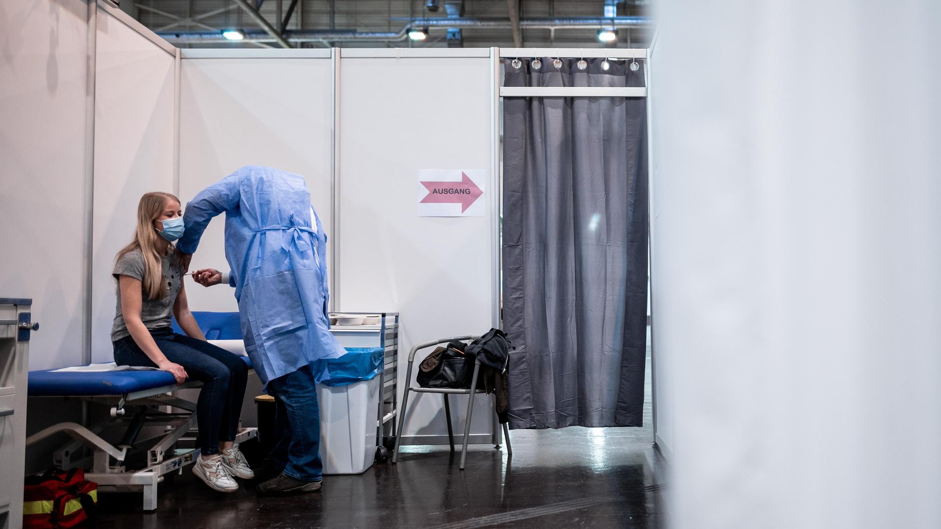 Eine Frau sitzt in einer Impfkabine im Impfzentrum in Essen und bekommt den Impfstoff von Biontech/Pfizer gespritzt. Eine Frau sitzt in einer Impfkabine im Impfzentrum in Essen und bekommt den Impfstoff von Biontech/Pfizer gespritzt.