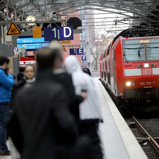 Ein Regionalexpress fährt in den Hauptbahnhof Köln ein, Menschen warten am Gleis.