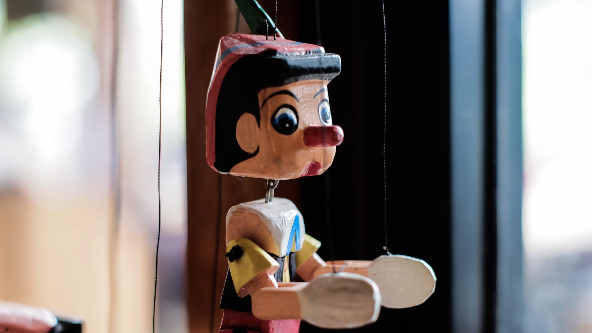 Eine Marionette mit bunter Kleidung und der typischen langen Pinocchio-Nase.
