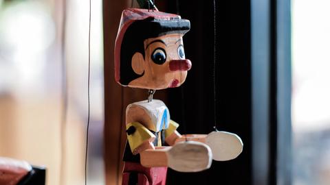 Eine Marionette mit bunter Kleidung und der typischen langen Pinocchio-Nase.