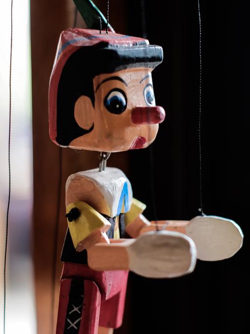 Eine Marionette mit bunter Kleidung und der typischen langen Pinocchio-Nase.