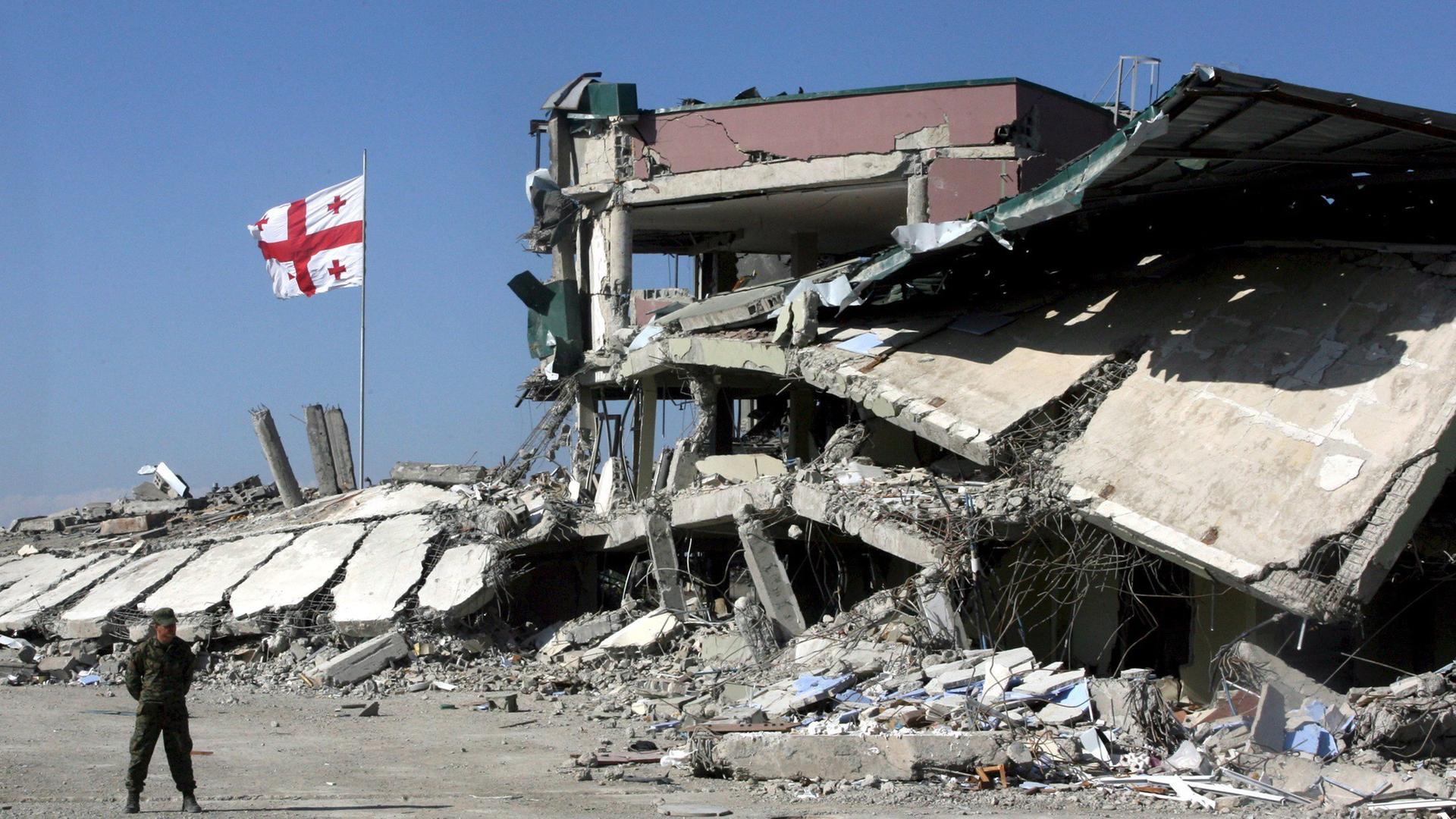 Das Bild zeigt eine zerstörte Militärbasis und eine Flagge von Georgien im Jahr 2008 Das Bild zeigt eine zerstörte Militärbasis und eine Flagge von Georgien im Jahr 2008