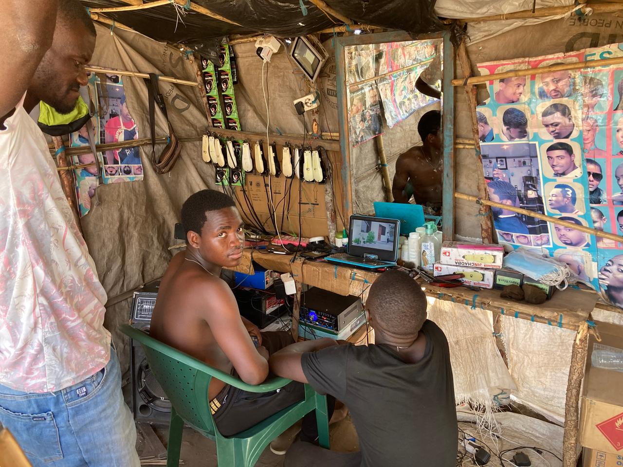 Junge Männer in einem provisorischen Friseursalon in einem Flüchtlingscamp in Mosambik.