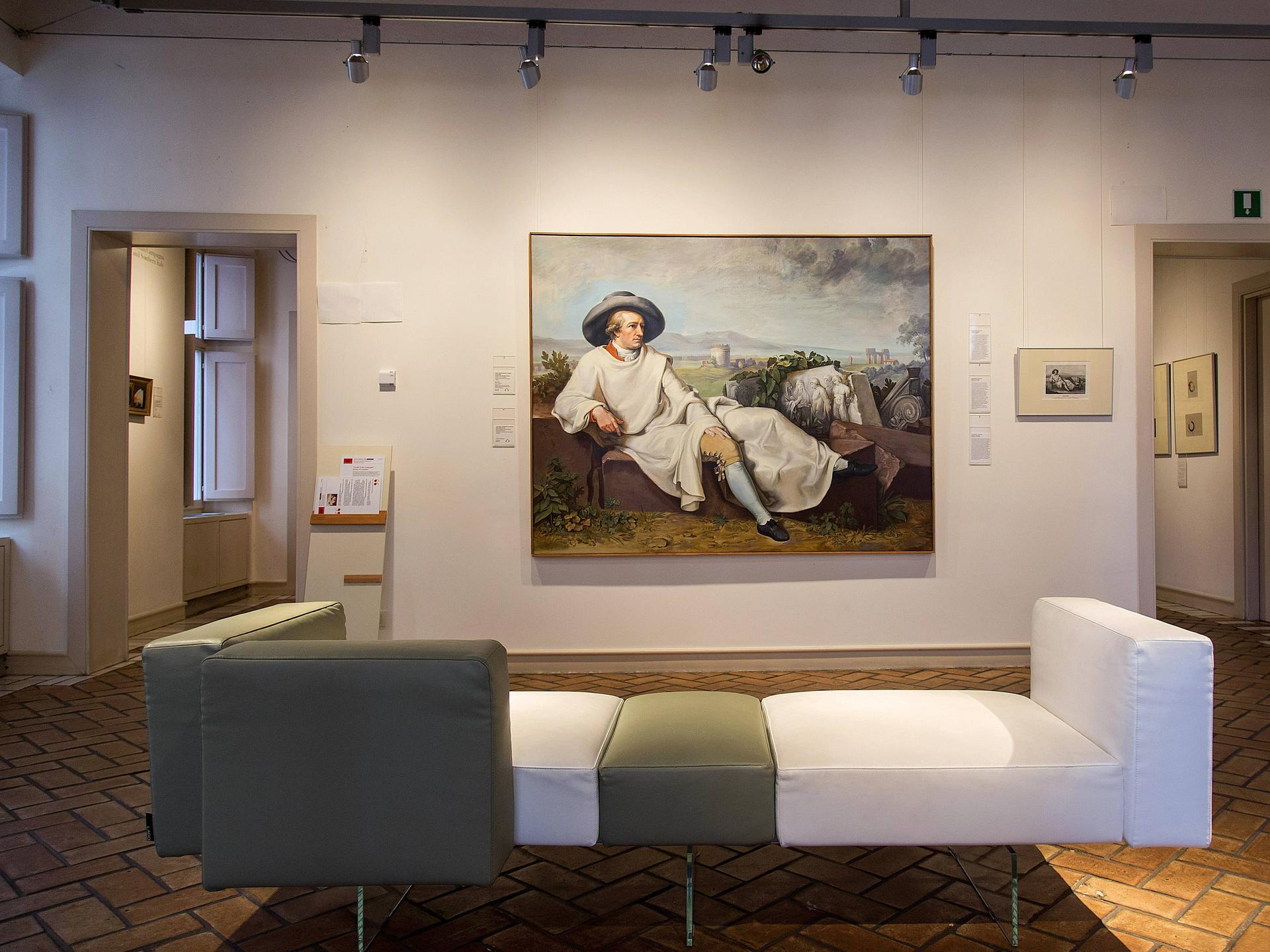 Im Museum Casa di Goethe in Rom hängt eine Kopie des Gemäldes Goethe in der Campagna. Zu sehen ist hier der Ausstellungsraum mit einem Sitzmöbel im Vordergrund. 
